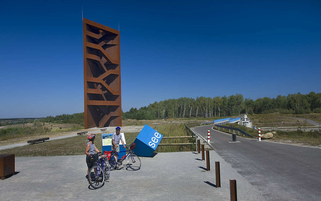 Radfahrer an der Landmarke Rostiger Nagel am Sedlitzer See