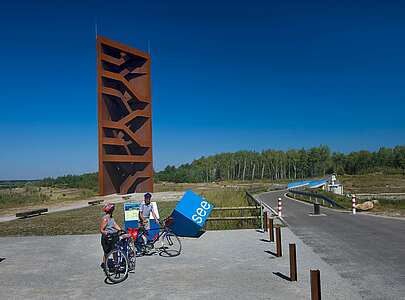 Radfahrer an der Landmarke Rostiger Nagel am Sedlitzer See